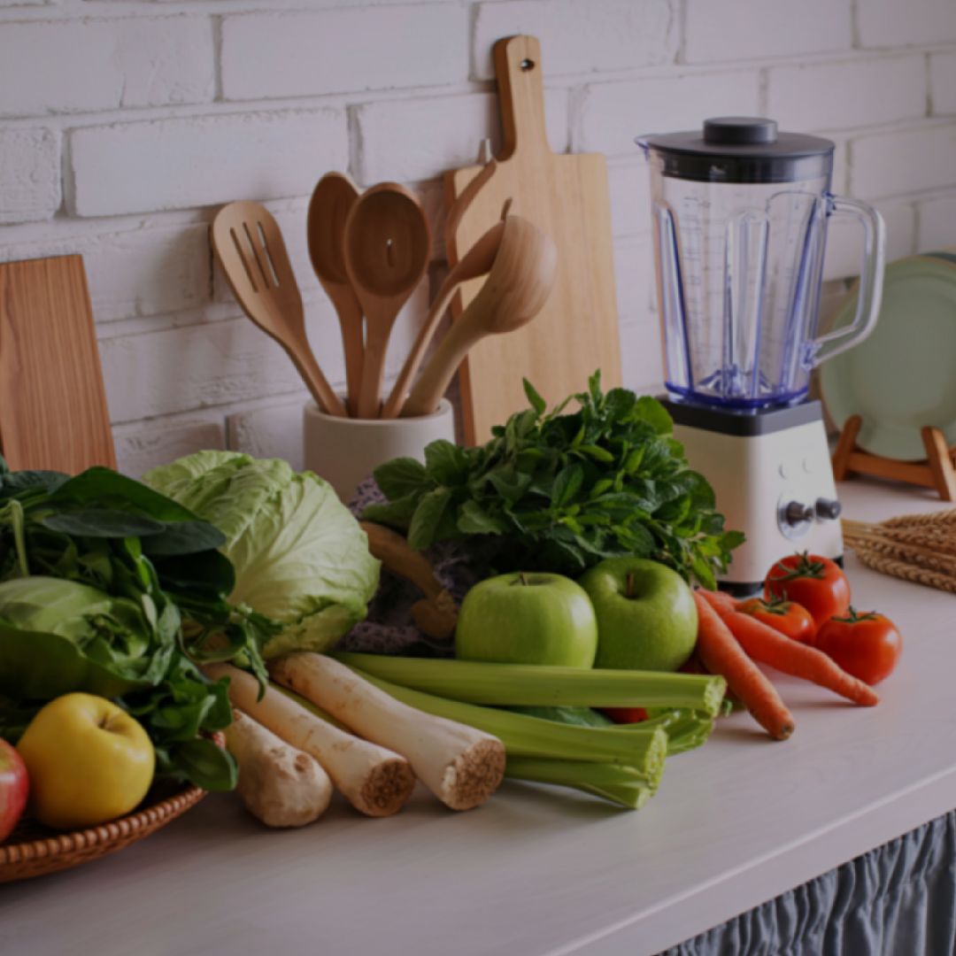 Kitchen counter with fresh produce, a blender, and wooden utensils.